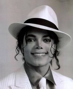 a man in a white suit and blue shirt wearing a black and white fedora