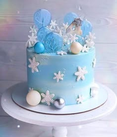 a blue frosted cake decorated with snowflakes and ornaments