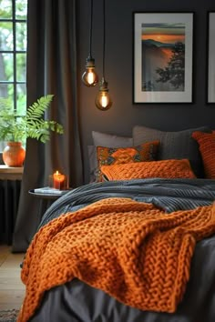 a bedroom with orange and gray bedding, pictures on the wall and two hanging lights