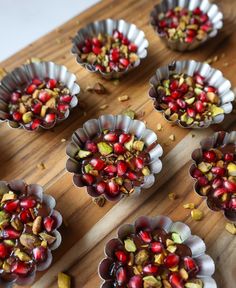 several bowls filled with nuts and pomegranates on top of a wooden table