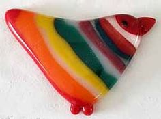 a multicolored triangle shaped glass object on a white surface with red, yellow, green, and blue stripes