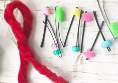 several different colored hair clips on top of a white wooden table next to a red string