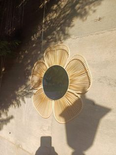 the shadow of a person standing in front of a wall with a flower shaped mirror