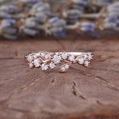 a close up of a ring on top of a piece of wood with flowers in the background