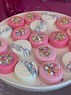 there are many pink and white cakes with sprinkles on the cake plate