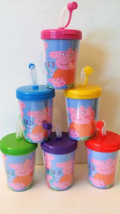 the children's cups have peppa pig faces on them and are sitting next to each other