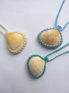 three seashells are shown on a white surface, one is blue and the other is yellow