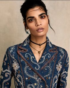 a woman wearing a blue shirt and black choker is standing in front of a wall