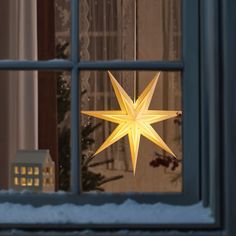 a lighted star hanging from the side of a window