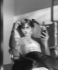 black and white photograph of a shirtless man taking a selfie with his cell phone