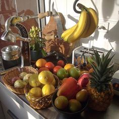 there are many different types of fruits on the counter in front of the kitchen sink