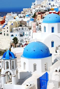 blue and white buildings on top of a hill with ocean in the backgroud