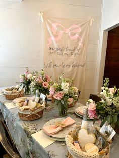 a table is set up with flowers, bread and pastries for a bridal party