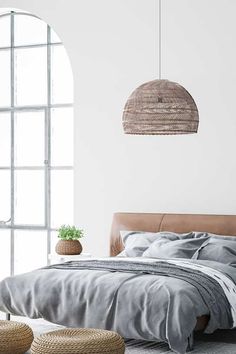 a bedroom with white walls and grey bedding, wicker baskets hanging from the ceiling