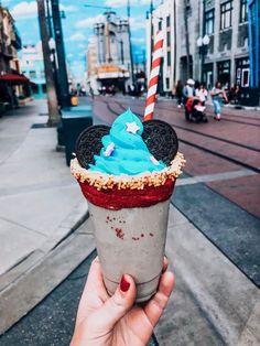 a person holding up an ice cream sundae with mickey mouse ears on it's top