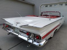 an old car parked in front of a garage