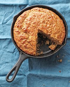 a cake in a cast iron skillet on a blue tablecloth with a slice missing