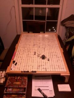 a board game sitting on top of a wooden table next to a pen and paper