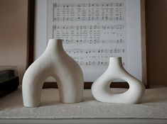 two white vases sitting on top of a table