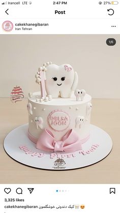 a white cake with pink frosting and an animal on top is sitting on a table