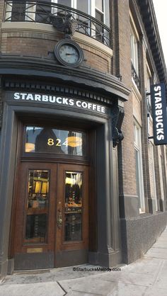 the entrance to starbucks coffee is shown in front of a brick building with a clock on it's side