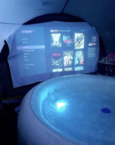 an inflatable hot tub next to a screen with movies on it and a chair