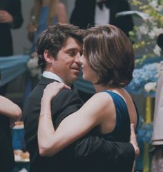 a man and woman embracing each other at a formal event