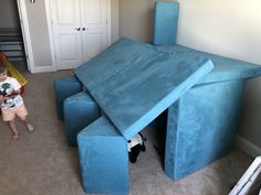 a young boy standing in front of a large blue couch that is shaped like a house