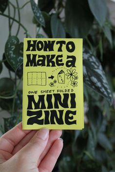 someone holding up a yellow sticker that says how to make a mini zine