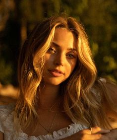 a woman with long blonde hair wearing a white top