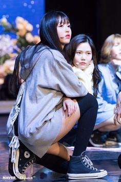 two young women sitting on the ground with their legs crossed