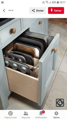 an open drawer in the middle of a kitchen with pots and pans on it