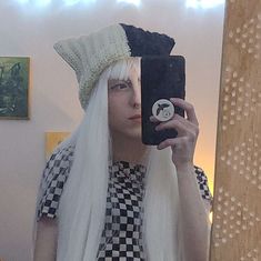 a woman with white hair is taking a selfie in front of a mirror wearing a wig