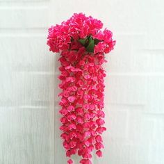 a bunch of pink flowers hanging from the side of a wall