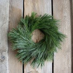 a close up of a green wreath on a wooden surface with wood planks behind it