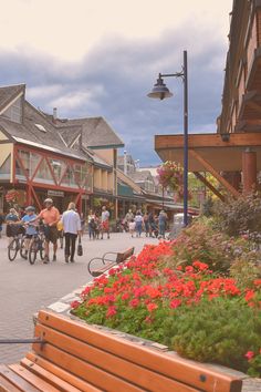 people walking and riding bikes on a city street with flowers in the foreground,