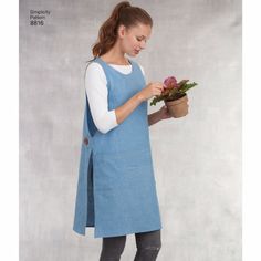 a woman is holding a potted plant and looking at the flowers in her hand