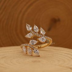 a gold ring with three pear shaped diamonds on it, sitting on top of a piece of wood