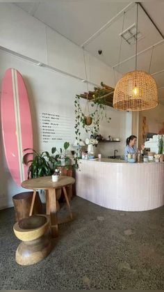 a surfboard is hanging from the ceiling in a room with two tables and stools