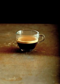 a glass cup filled with liquid sitting on top of a wooden table