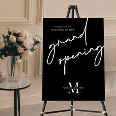 a sign that says grand opening next to a vase with flowers