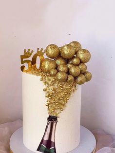 a white cake with gold decorations and a champagne bottle