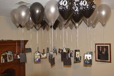 a bunch of balloons hanging from the ceiling with pictures on them and photos pinned to it