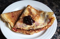 two crepes on a white plate with jam