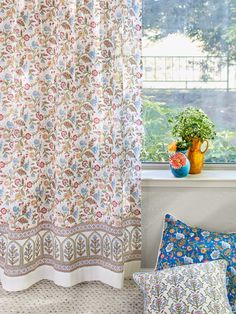 a window with curtains and pillows in front of it next to a potted plant