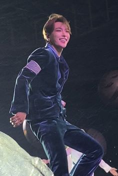 a young man riding a skateboard on top of a large white rock in the dark