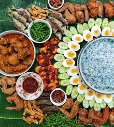 an assortment of food is arranged on a banana leaf