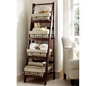 a ladder shelf with baskets on top of it in front of a white chair and window