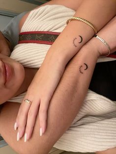 two people with matching tattoos on their arms, one holding the other's arm