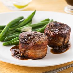 some meat and green beans on a white plate